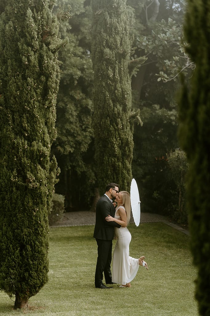 Romantic shot of the couple framed by the hotel's lush greenery and unique architectural details.