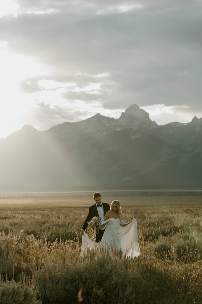Couple in a vast field with Tetons in background for their Jackson Hole elopement