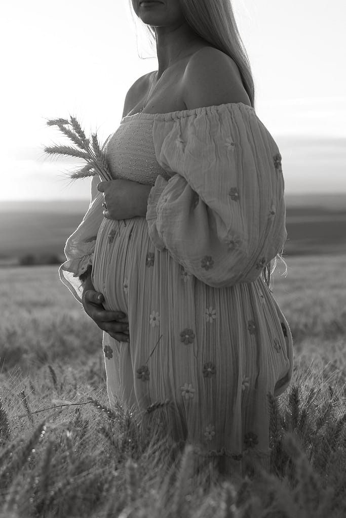 Haley wearing a flowing dress, her baby bump beautifully showcased amidst the golden wheat.