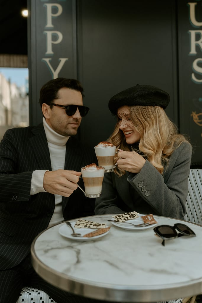 A couple sits at a charming Parisian cafe, enjoying coffee and each other's company against the backdrop of a quaint street scene.