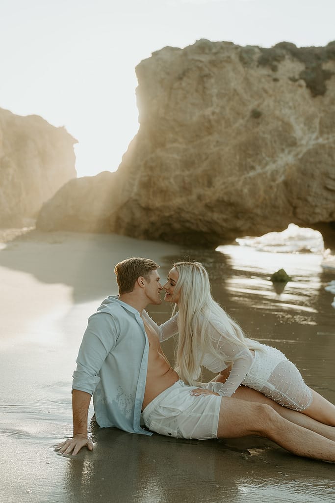Romantic moment as couple shares a kiss with the sun rising over the Malibu horizon.